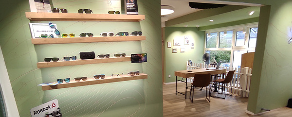 Präsentation moderner Sonnenbrillen auf Holzregalen in einem stilvollen Optikerladen.